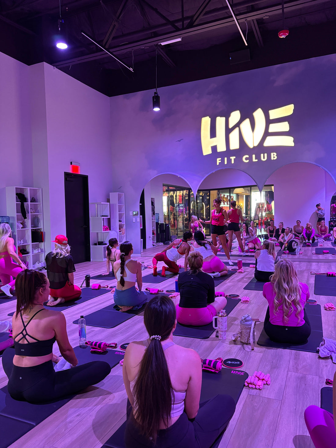 Group fitness class, people on yoga mats facing fitness instructor