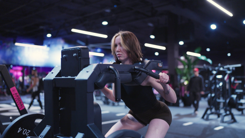 A woman exercises on a gym machine, focusing on her workout in a well-equipped fitness center.